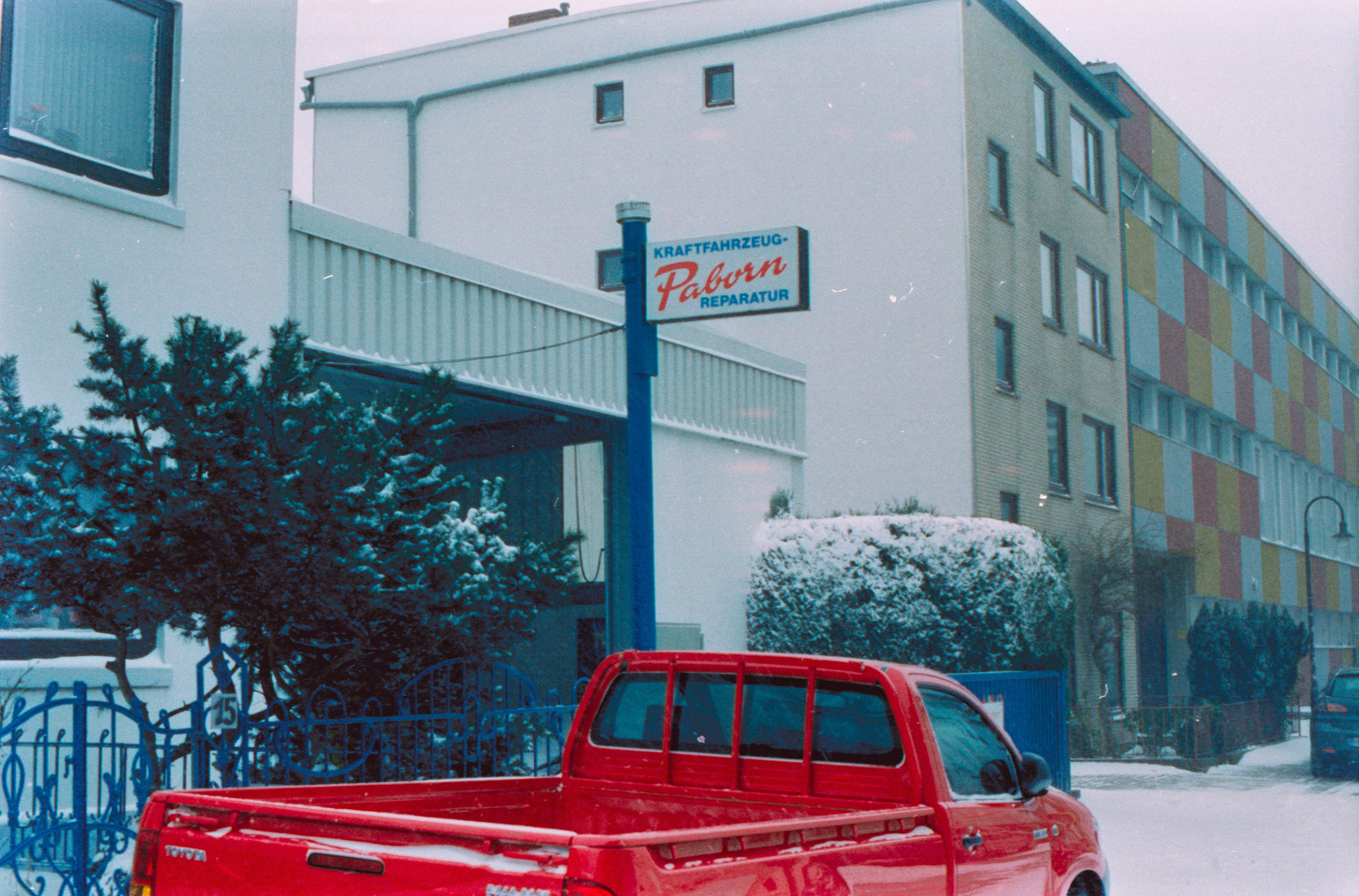 red crew cab pickup truck parked near white building during daytime